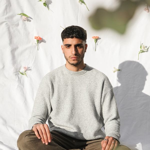 Silhouette of a person meditating against a simple background.