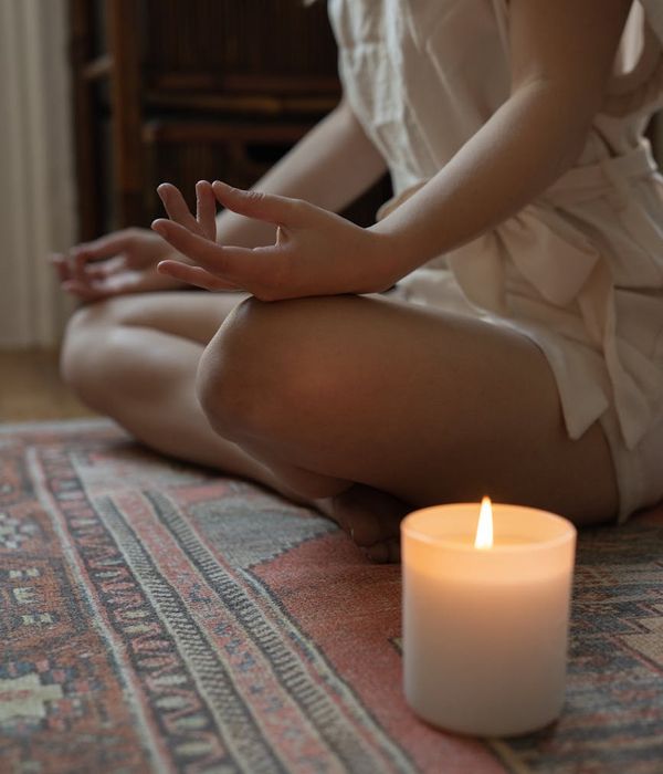 Woman in a calming yoga pose, bathed in fuchsia light.
